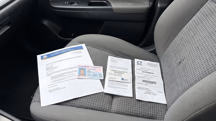 Connecticut DMV driving test documents and learner's permit on car seat